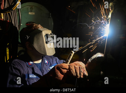 Hull Maintenance Technician 2nd Class Levi Malone performs welding in the general workshop aboard the guided-missile cruiser USS Stock Photo
