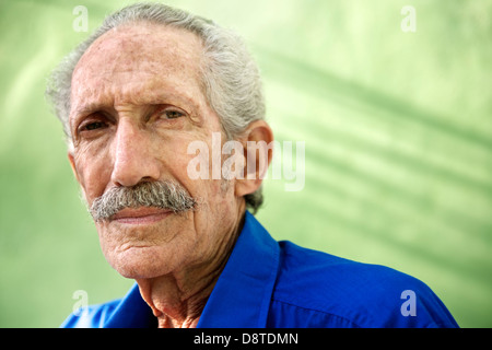 Elderly people and emotions, portrait of serious senior caucasian man looking at camera against green wall Stock Photo