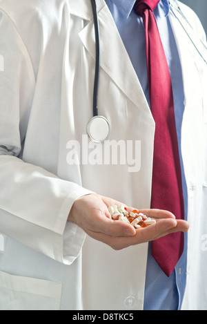 Male doctor with hand full of pills, close up image with shallow depth of filed with focus on hand with cure. Stock Photo