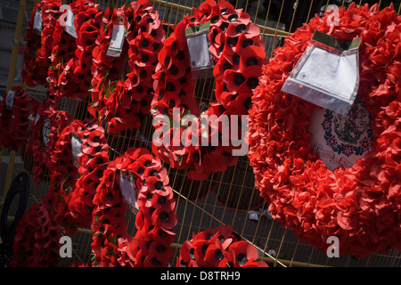 Dedicated to the casualties of wars, red artificial poppies set into wreaths hang on temporary fencing in London's Whitehall. Stock Photo