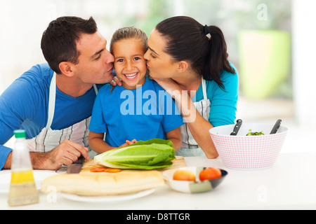 loving parents kissing little daughter in kitchen Stock Photo
