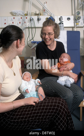two young mothers with premature babies chatting in hospital ward Stock Photo