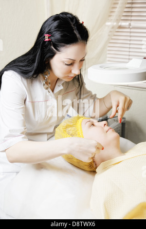 Beautician makes threading hair removal Stock Photo