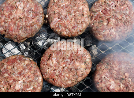 Red meat burgers cooking on outdoor barbecue grill. Stock Photo