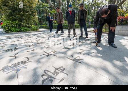 Shanghai, China - April 7, 2013: man writing chinese calligraphy with water in fuxing park at the city of Shanghai in China on april 7th, 2013 Stock Photo
