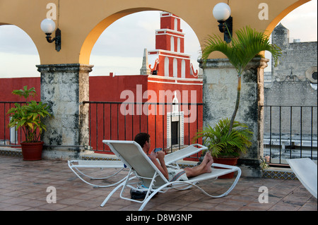 Young man using a smart phone while relaxing on the rooftop of the Hotel Caribe in Merida, Yucatan, Mexico Stock Photo