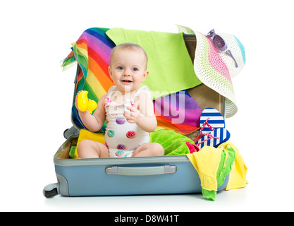 Baby girl sitting in suitcase with things for vacation travel Stock Photo