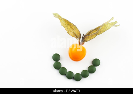 Green chlorella algae tablets in a smile and fresh golden berry Stock Photo