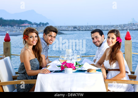 Two happy couples having dinner at the seaside. Stock Photo