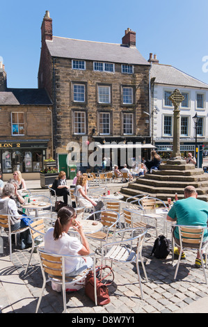 People sitting eating drinking within Alnwick market square, Northumberland, England, UK Stock Photo