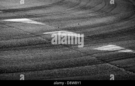 Abstract turning road background with tires track and white triangle signs on dark asphalt Stock Photo