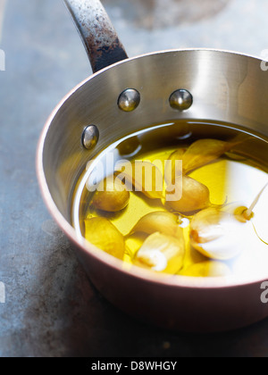 Cloves of garlic in a saucepan of olive oil Stock Photo