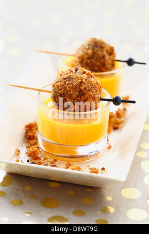 Cream of carrot soup with foie gras balls coated in crumled gingerbread Stock Photo