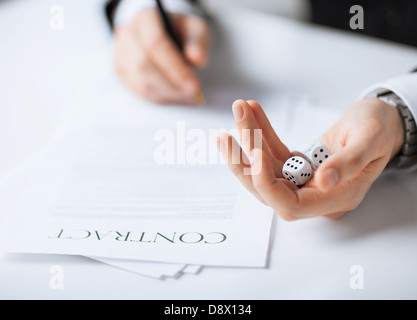 man hands with gambling dices signing contract Stock Photo
