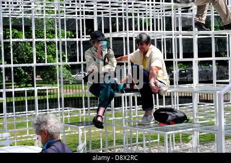 A couple relaxing in the Serpentine Gallery pavilion, designed by Sou Fujimoto. London, United Kingdom. Stock Photo