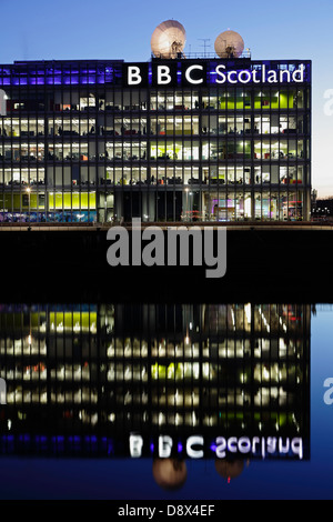 The illuminated BBC Scotland Headquarters on Pacific Quay reflected in the River Clyde at sunset, Glasgow, Scotland, UK Stock Photo