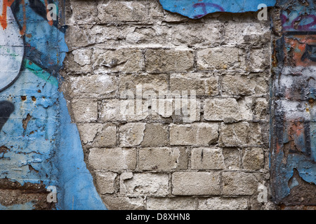Aged weathered brick wall with blue graffiti Stock Photo