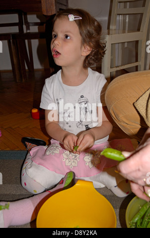 4 year old little girl shelling peas at home Stock Photo