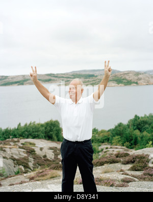 A man standing by the sea making a victory sign. Stock Photo