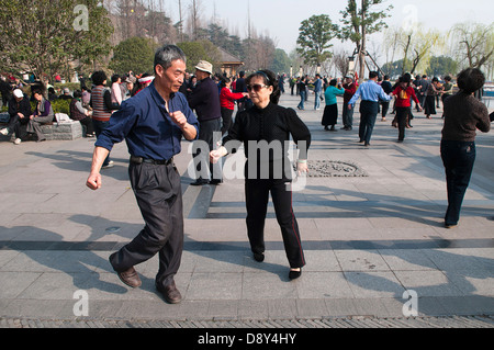 Retired couples dancing beneath the Ming city wall at Xuanwu Lake Park Couple in foreground swinging arms in modern dance Asia Stock Photo