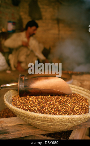 Roasted chickpeas. In the background, a man is roasting chickpeas ( India) Stock Photo