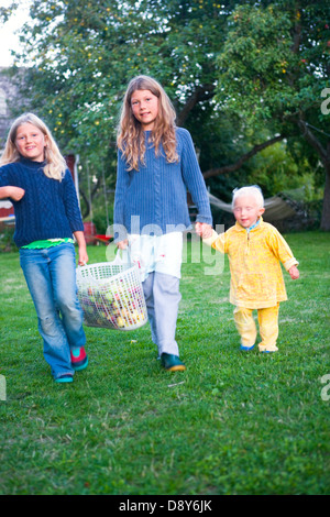 Three girls who have picked apples in a garden. Stock Photo