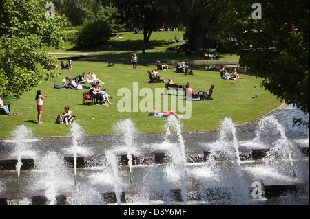 A woman reads on a field in the sun in the park 'Planten un Blomen' in Hamburg, Germany, 06 June 2013. Photo: CHRISTIAN CHARISIUS Stock Photo