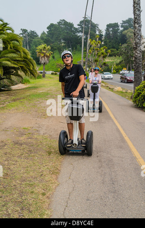 A group of Segway personal transporter riders wearing helmets drive their Segways on a bicycle path in Santa Barbara, California Stock Photo