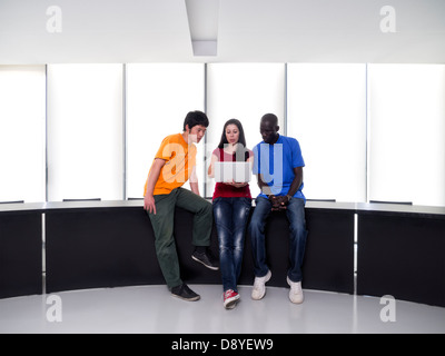 Black man, asian man and caucasian woman gathered around a laptop computer Stock Photo