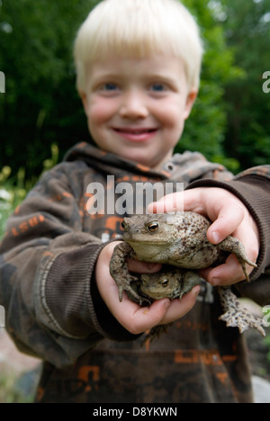 A blond boy holding toads. Stock Photo