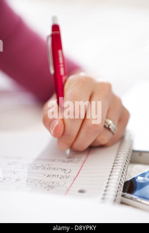 Close-up of womans hand writing on notebook Stock Photo