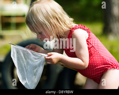 Girl looking into butterfly net Stock Photo