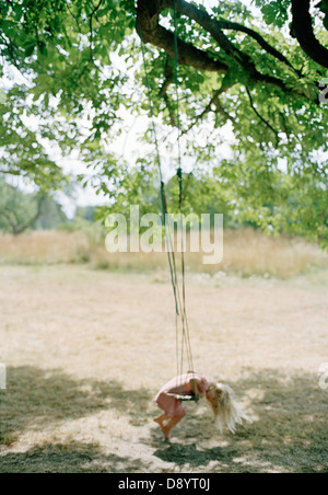 Girl playing with a swing hanging from a tree. Stock Photo