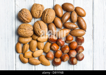 various unpeeled nuts on wooden table Stock Photo