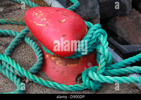 Red mooring bollard with green naval rope Stock Photo