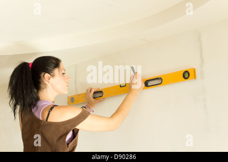 DIY young attractive woman using spirit level to work out measurements. Stock Photo