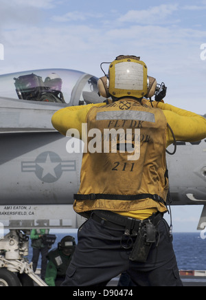 A US Navy sailor directs an F/A-18E Super Hornet fighter aircraft into position on the flight deck of the aircraft carrier USS Nimitz June 4, 2013 in the Indian Ocean June 4, 2013. The Nimitz was underway in the U.S. 7th Fleet area of responsibility conducting maritime security operations and theater security cooperation efforts. (U.S. Navy photo by Mass Communication Specialist 3rd Class Devin Wray/Released) Stock Photo