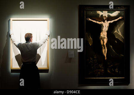 London, UK. 7th June 2013. A Sotheby's employee holds a work entitled 'Concetto Spaziale Attese ' by Lucio Fontana (Est. £3.3-4.5 million) which stands next to El Greco’s “Christ on the cross” (Est. £3-5 million) during the preview of this summer auction at Sotheby's estimated at £100 million. Credit:  Piero Cruciatti/Alamy Live News Stock Photo