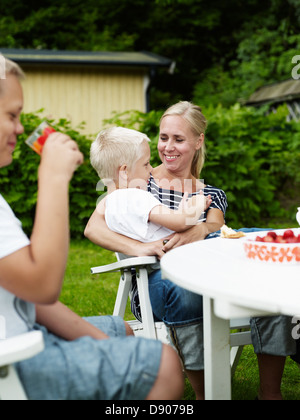 Mother with two sons relaxing in back yard Stock Photo