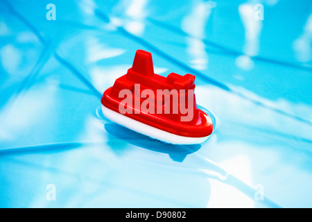 A red plastic boat floating in a swimming-pool. Stock Photo