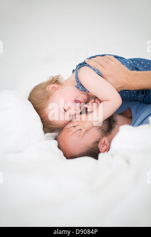 Man and little daughter lying in bed Stock Photo