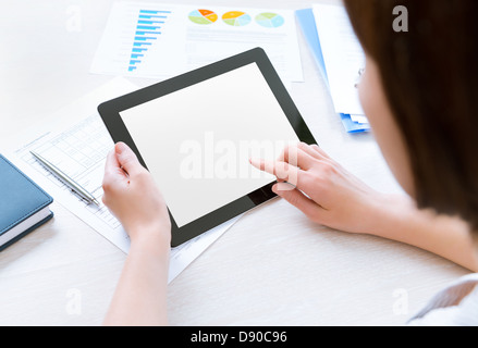 Caucasian businesswoman sitting at workplace and looking on blank modern digital tablet, touching on empty screen Stock Photo