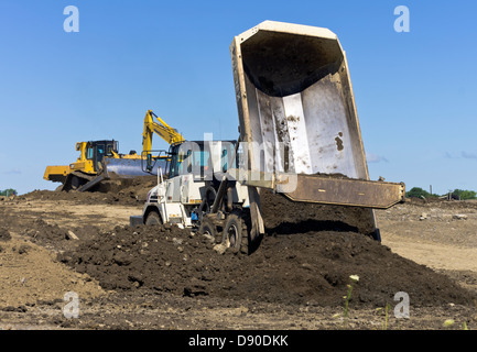 Dump truck unloading earth on construction site Stock Photo