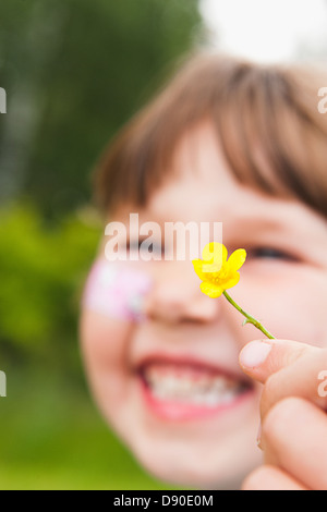 A girl laughing holding a yellow flower. Stock Photo