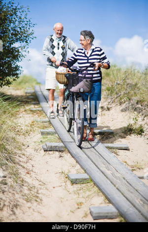 Senior couple with bicycles on dunes Stock Photo