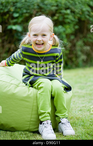 Girl sitting on a bean bag reading a book Stock Photo - Alamy
