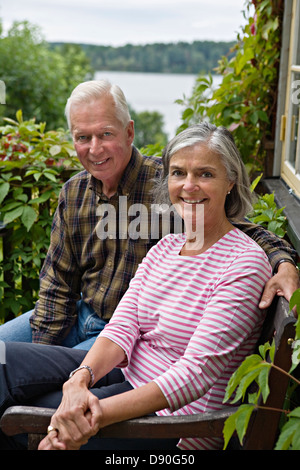 Senior couple sitting on bench, smiling Stock Photo