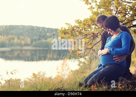 Mid adult couple sitting near by lake Stock Photo