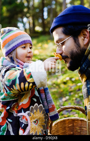 Father and daughter smelling mushrooms in forest Stock Photo