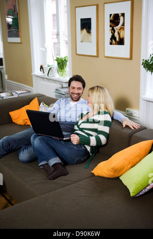 A couple with a computer in a sofa. Stock Photo